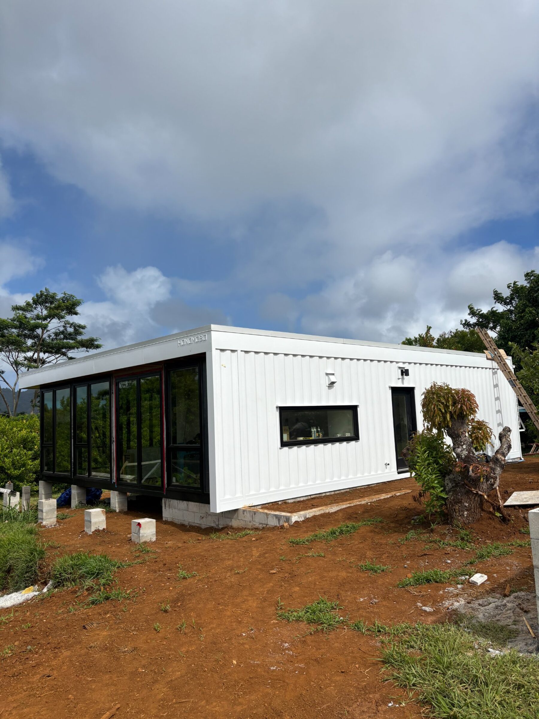 Honomobo HO4 on Kauai — charcoal and white module with floor-to-ceiling glass and mountain backdrop